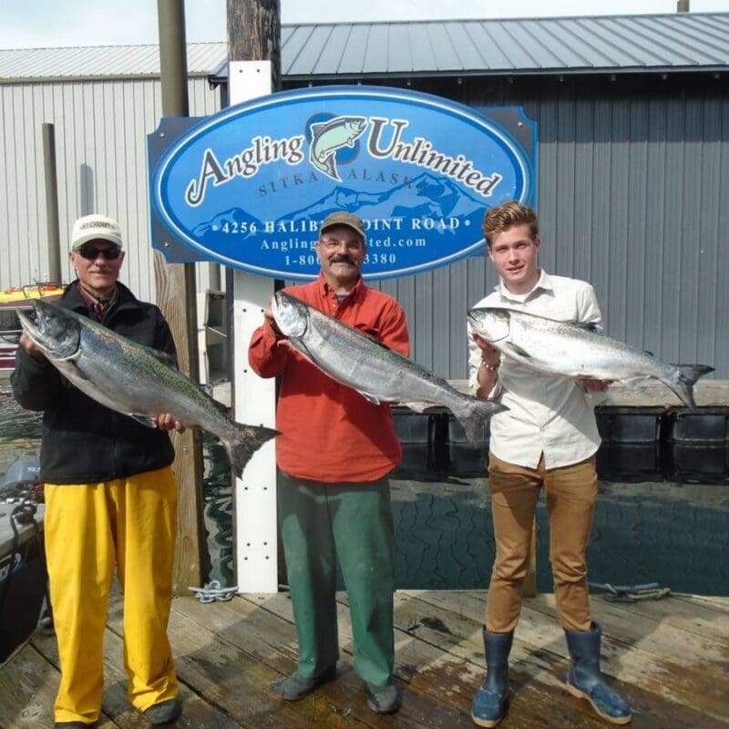 Angling Unlimited guests stand on the dock with salmon