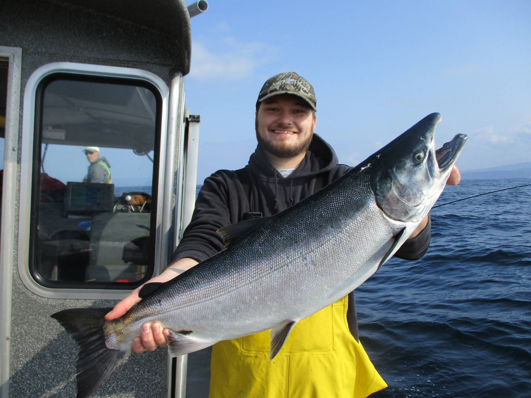 man holding large silver salmon on fishing boat