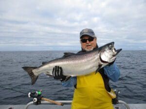 man holding large king salmon on boat