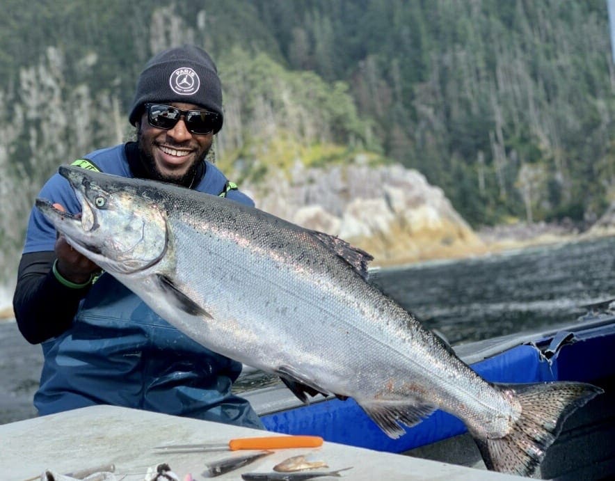 man in hat and glasses holding large salmon