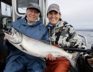 captain sarah and male guest holding large salmon