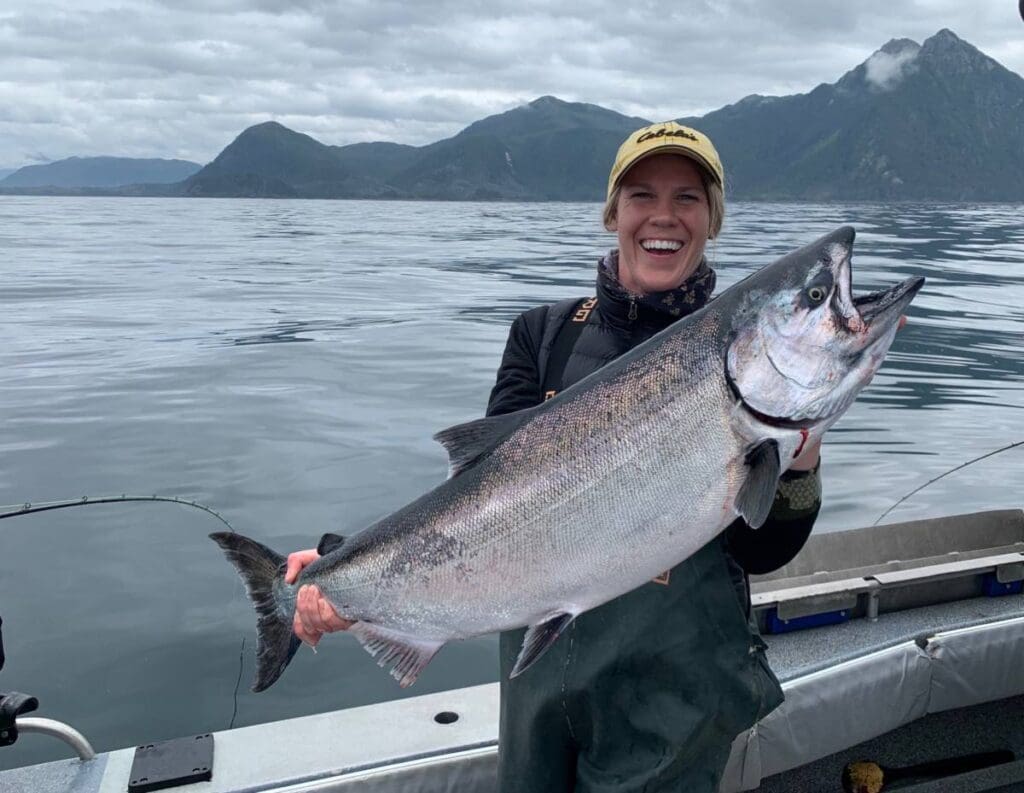 Woman smiles as she holds a large Alaskan King Salmon