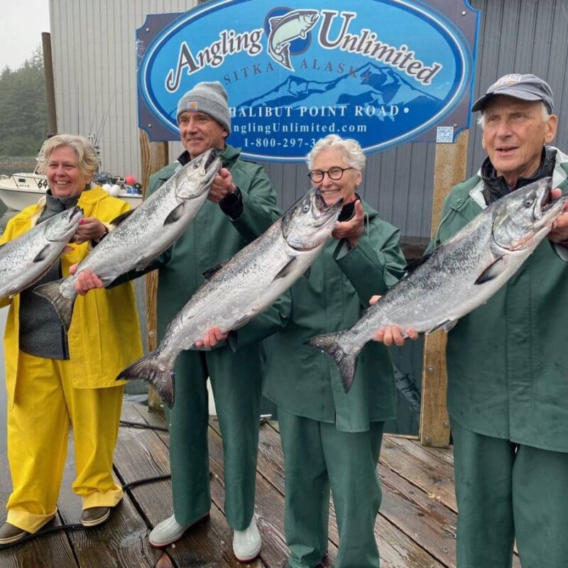 A group of fishers hold their king salmon catches in front on the Angling Unlimited dock