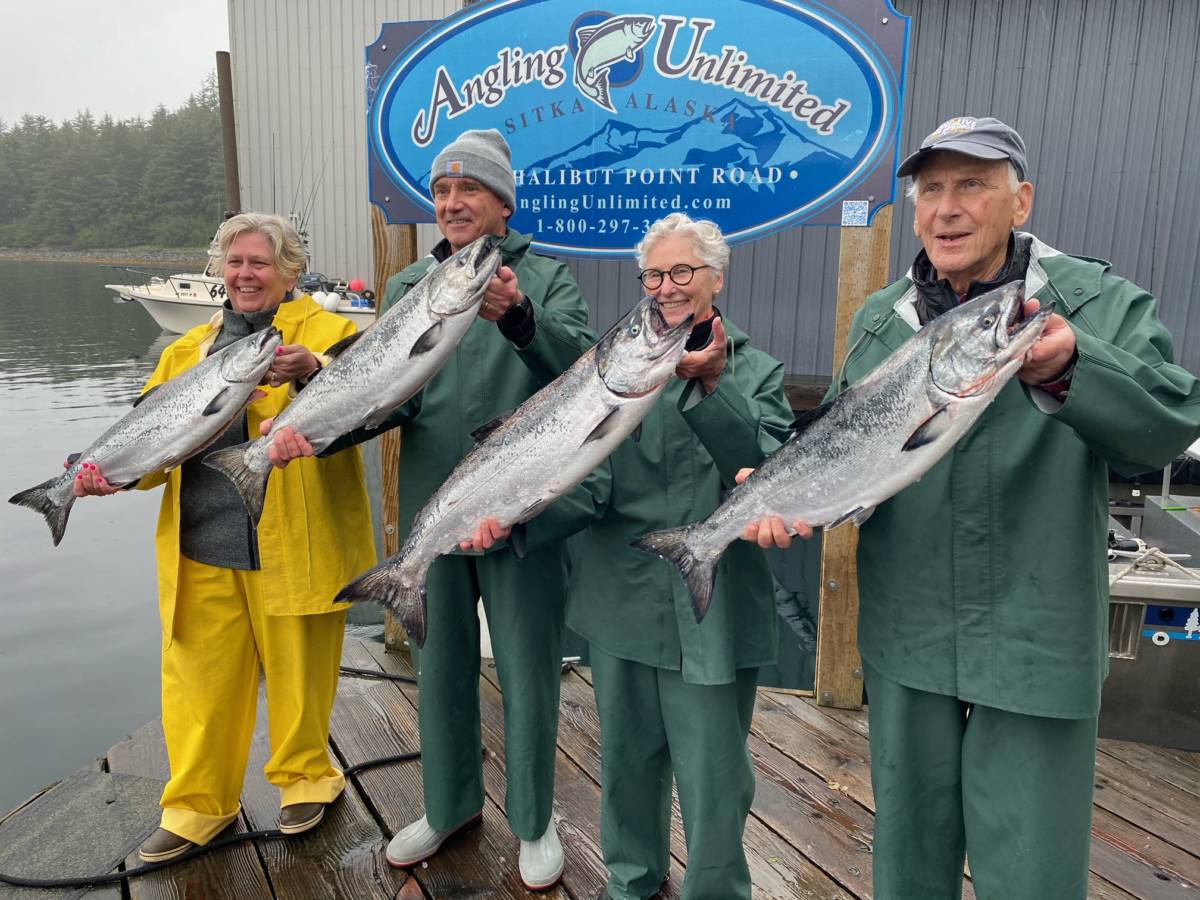 A group of fishers hold their king salmon catches in front on the Angling Unlimited dock