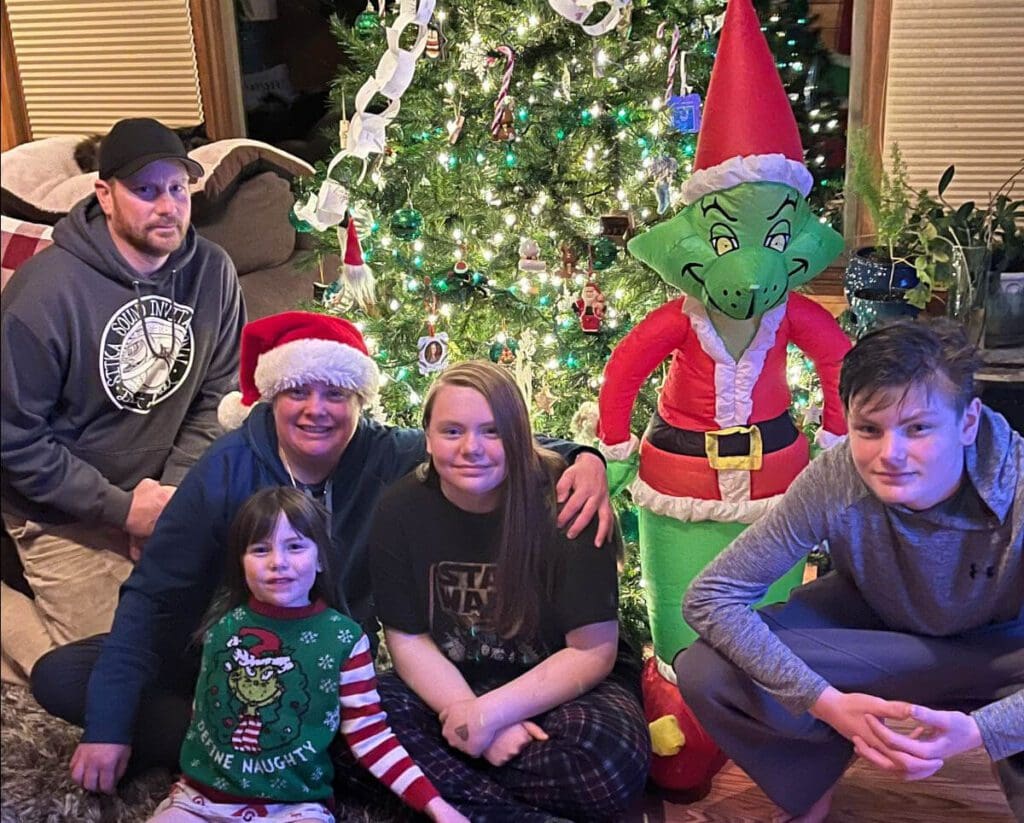 Family sits in front of Christmas tree