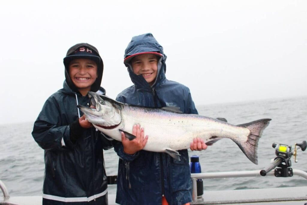 Two kids hold a king salmon on a boat in Sitka, Alaska