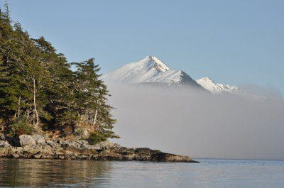 Mountains poking out of a fog bank in Sitka, Alaska above a body of water