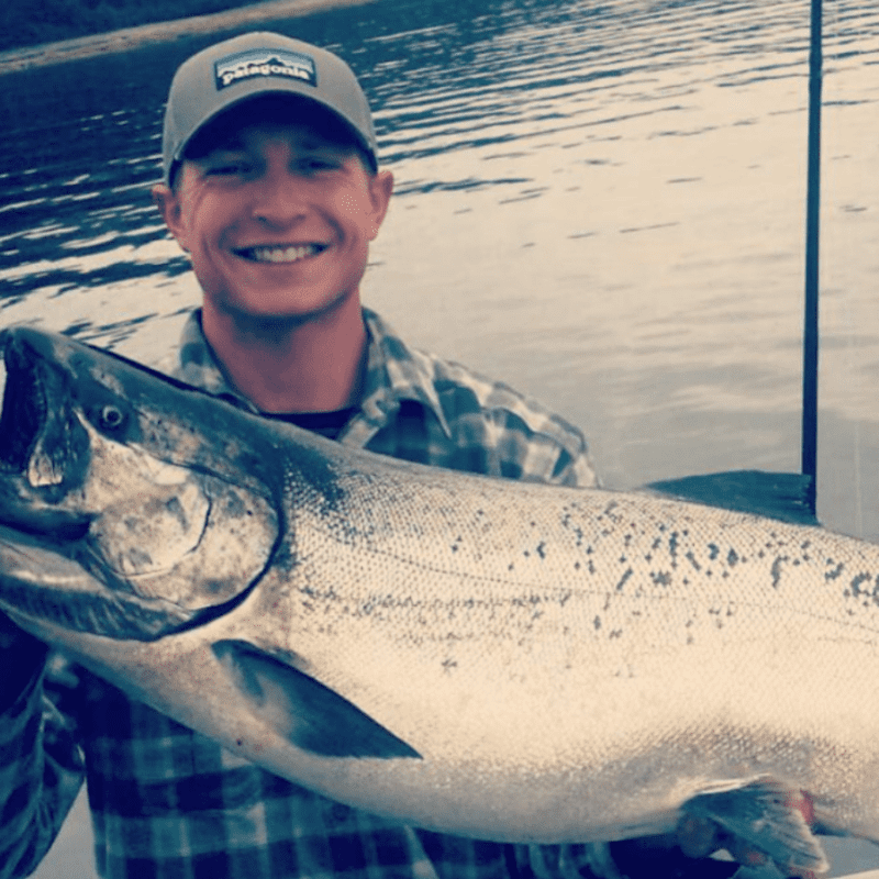 Angling Unlimited crew member Spencer Chute smiles as he holds a large salmon