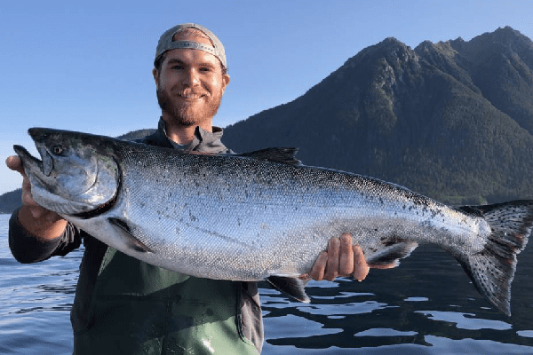 A man holds a large Chinook (king) salmon in Sitka, Alaska