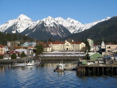 Large snow covered mountains stand behind buildings in Sitka, Alaska