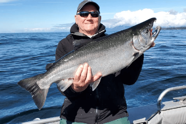 A man holds a coho (silver) salmon on a boat in Sitka, Alaska