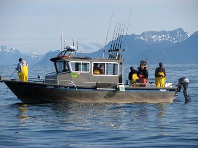 An Angling Unlimited fishing boat is stopped in the water with multiple people fishing off of it